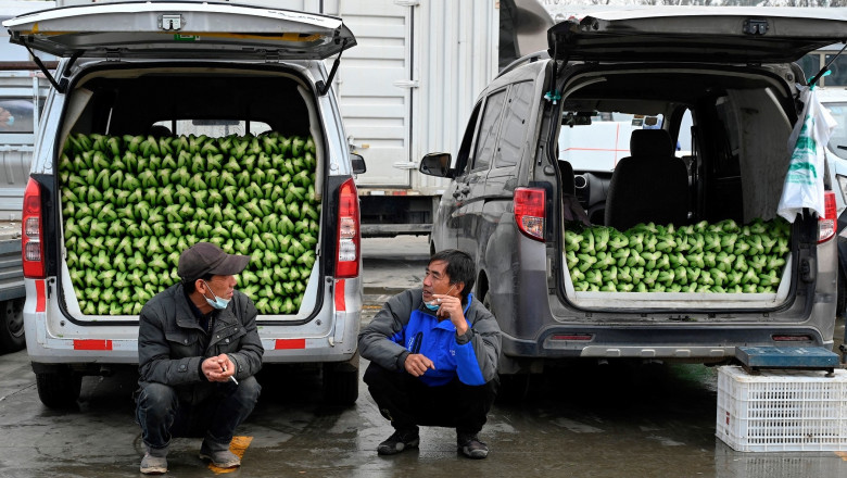 Two men chat in front of vans filled with vegetables at Xinfadi market, an outdoor wholesale market in Beijing on November 3, 2021
