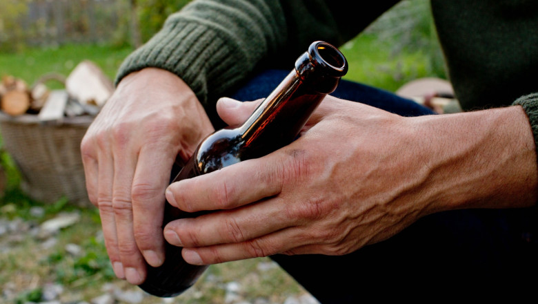 bărbat cu o sticlă de bere în maini