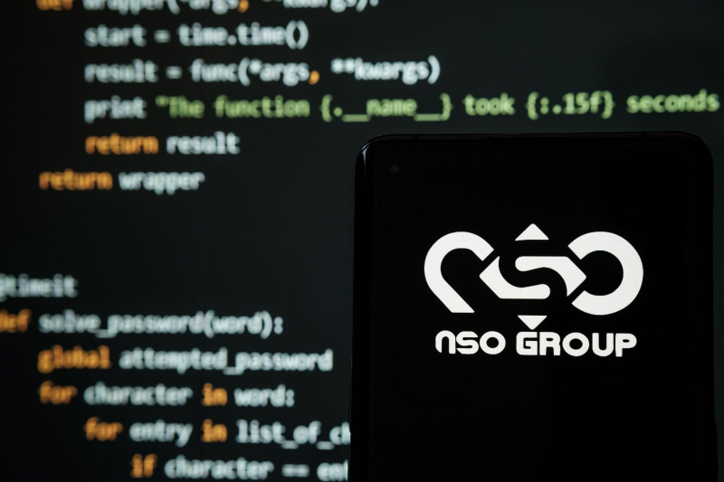 NSO Group logo seen on smartphone placed in front of laptop with simple hacking code. Selective focus. Stafford, United Kingdom, July 19, 2021.