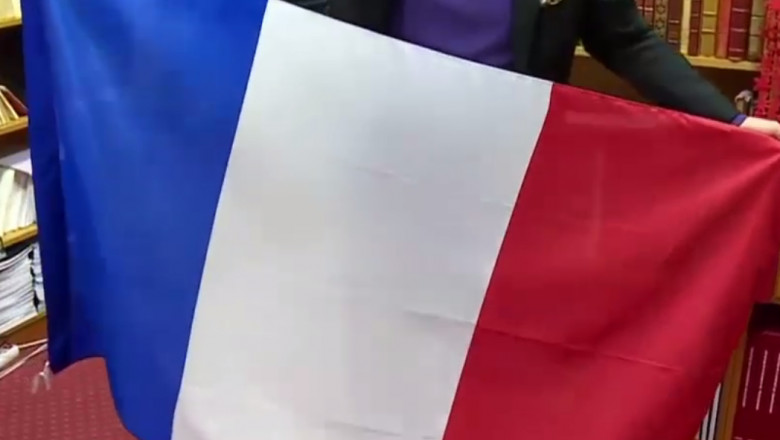 Un drapel al Franâei este desfășurat de un bărbat.
