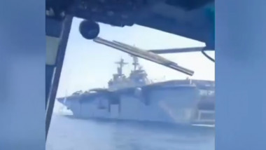 Navă americană de război văzută din interiorul unui elicopter care o survola.