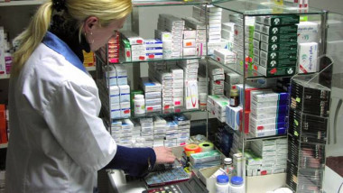 O farmacistă pregătește medicamente pentru clienți.