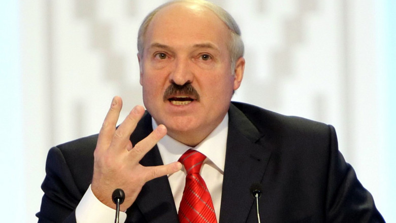Lukașenko în fața unui microfon gesticulează cu mâna