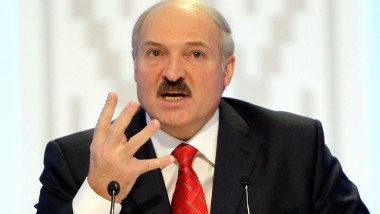 Lukașenko în fața unui microfon gesticulează cu mâna
