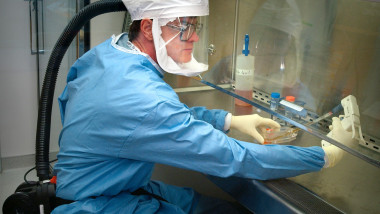 cercetator in echipament de protectie in laborator testeaza virusuri