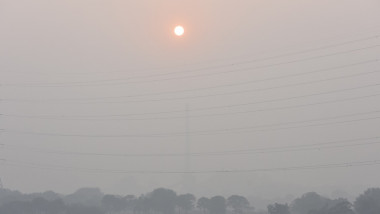 Fotografie cu cerul și Soarele ascuns în spatele fumului gros din New Delhi