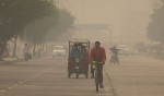 Oameni care merg pe o stradă din New Delhi, în fumul gros produs de arderea de deșeuri