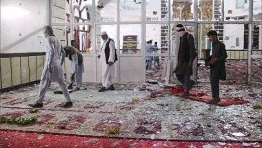 Bărbați care merg prin cioburi de la ferestre după o explozie la o moschee în estul Afganistanului