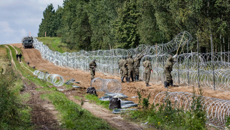 soldati polonezi care ridica un gard de sarma ghimpata la granita cu belarus