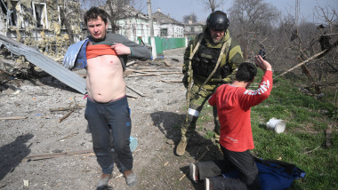 Un soldat din armata lui Kadîrov percheziționează doi civili ucraineni neînarmați