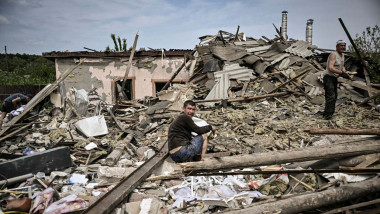 A man sits at the debris of a destoyed house after a missile strike in the city of Sloviansk in the eastern Ukrainian region of Donbas