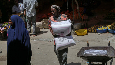 femeie africana duce 3 saci cu cereale intr-o piata din africa