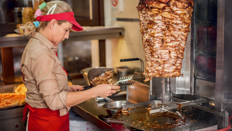 Chef preparing roasted sliced gyros meat in fast food restaurant