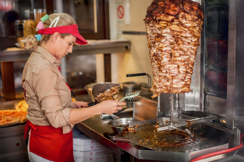 Chef preparing roasted sliced gyros meat in fast food restaurant