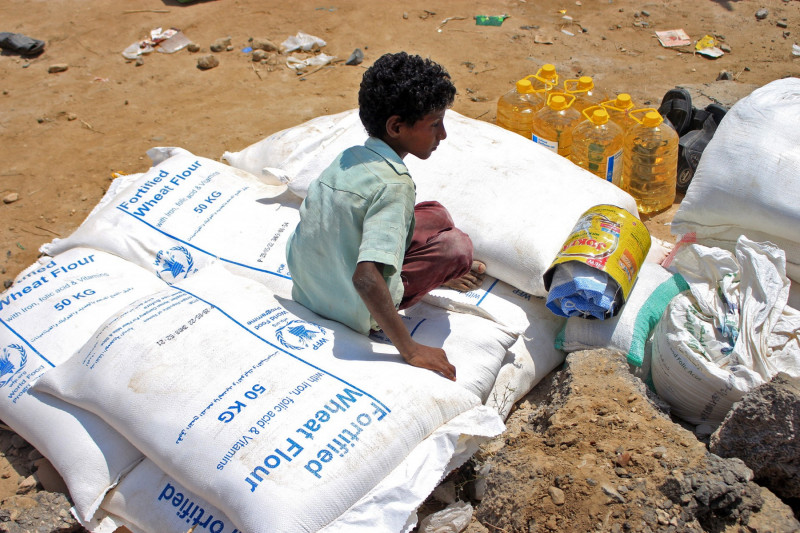 Copil stă pe un sac cu ajutoare al Programului Alimentar Global din Yemen