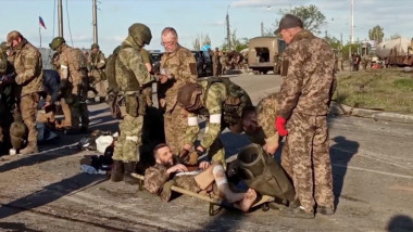 Militari ruși percheziționează prizonieri ucraineni.