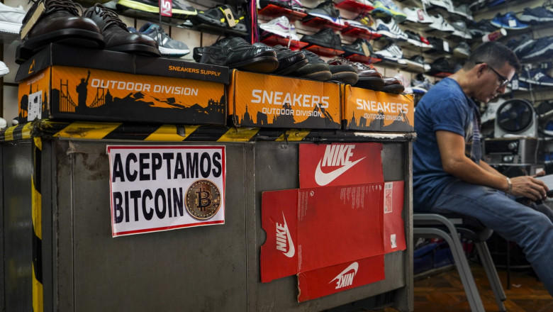 Stand de vânzare de pantofi în El Salvador cu un semn care transmite că este acceptată plata în bitcoin