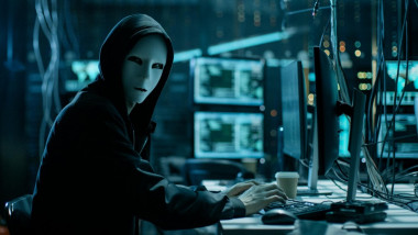 hacker cu masca in fata unui calculator