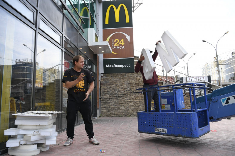 Doi bărbați scot logo-ul mcdonald's de pe un restaurant din Rusia