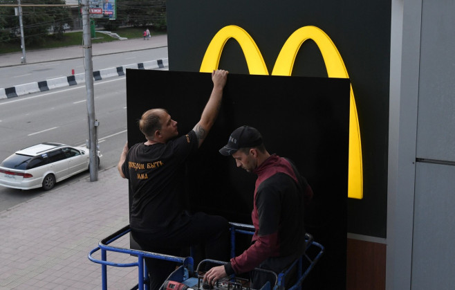 Doi bărbați acoperă logo-ul mcdonald's de pe un restaurant din Siberia