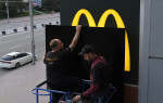 Doi bărbați acoperă logo-ul mcdonald's de pe un restaurant din Siberia