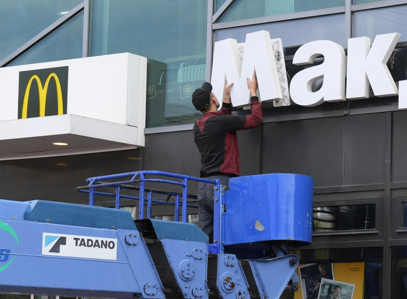 Doi bărbați scot logo-ul mcdonald's de pe un restaurant din Rusia