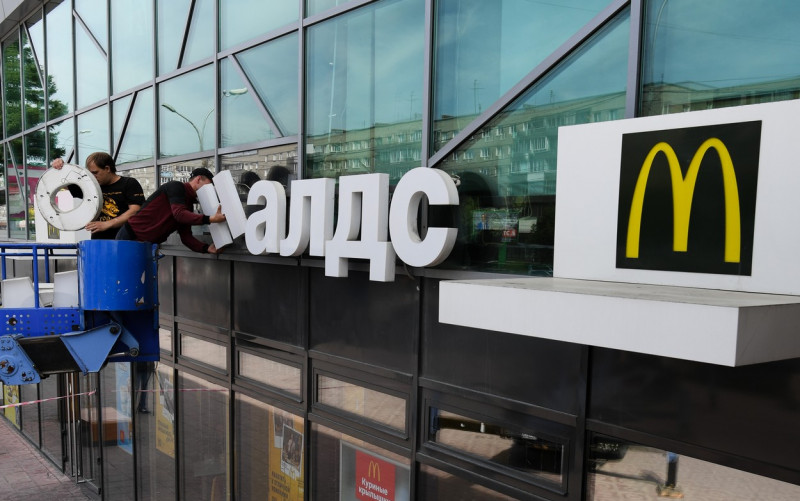 Doi bărbați scot logo-ul mcdonald's de pe un restaurant din Rusia