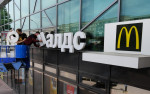 Doi bărbați scot logo-ul mcdonald's de pe un restaurant din Rusia