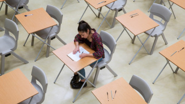 Elevated view of lone female student writing their GCSE exam in classroom