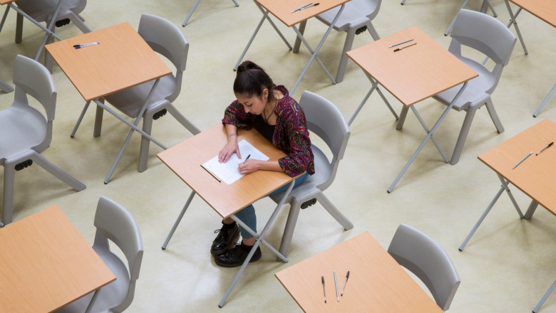 Elevated view of lone female student writing their GCSE exam in classroom