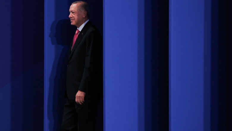 Președintele turc Recep Tayyip Erdogan. in picioare langa un perete albastru