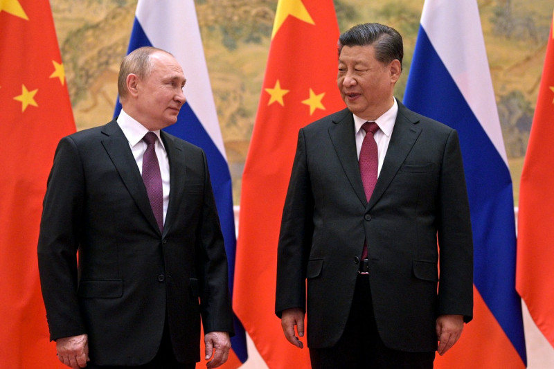 Putin îl privește pe Xi, cu steagurile Rusiei și Chinei în spate