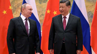 Putin îl privește pe Xi, cu steagurile Rusiei și Chinei în spate
