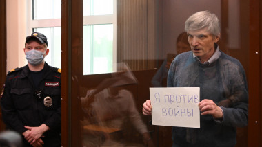 Moscow city deputy Alexei Gorinov, accused of spreading "false information" about the Russian army, holds a sheet of paper reading "I am against war" inside a glass cell during a hearing in his trial at a courthouse in Moscow