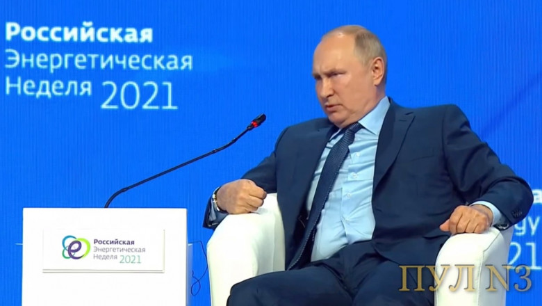 Vladimir Putin privește cu supărare spre un microfon, tolănit pe un fotoliu
