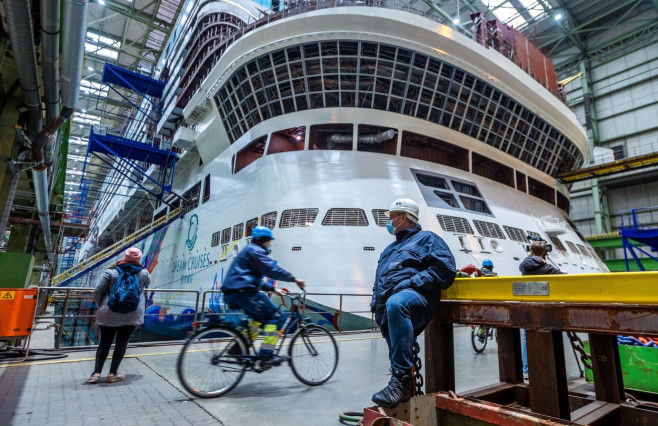 Wismar, Germany. 26th Jan, 2022. A shipbuilder waits in front of the stern of the "Global Dream" cruise ship under construction. The provisional insolvency administrator had informed the employees about the current situation at a works meeting. Investors