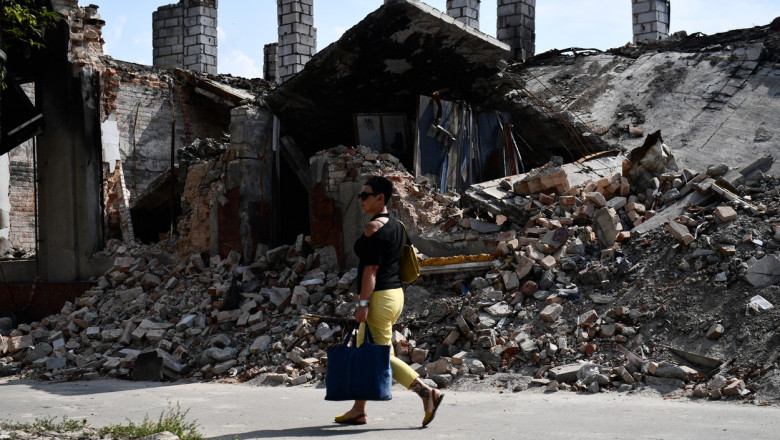 Femeie merge pe lângă o clădire în ruine în Donețk