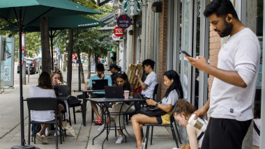 canadieni la terasa care se uita in telefoane si laptopuri
