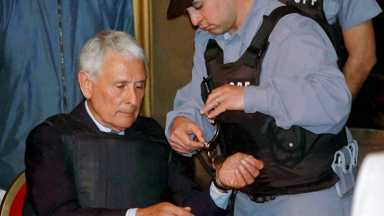 un polițist scoate cătușele de la mainile lui Miguel Etchecolatz