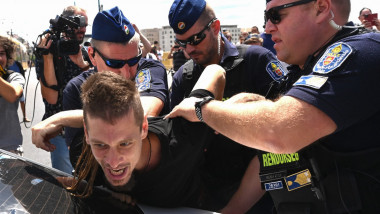 un tanar protestatar este tinut cu mainile la spate pe o masina de mai multi politisti unguri