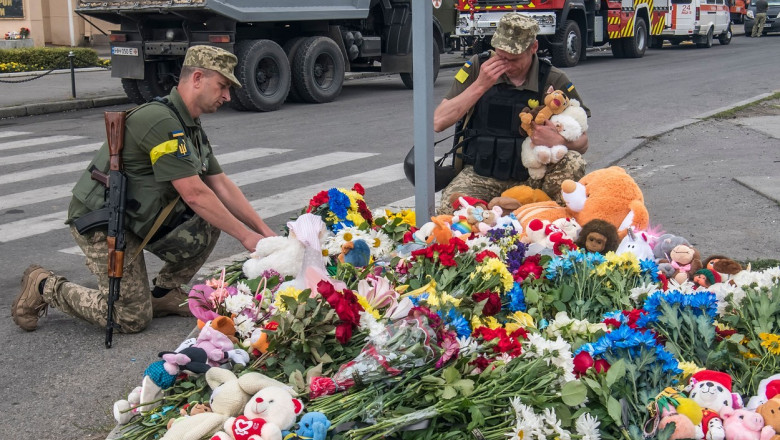 doi militari aranjeaza flori si ursuleti de plus la locul unde au murit o fetita de 4 ani intr-un atac rusesc la vinita