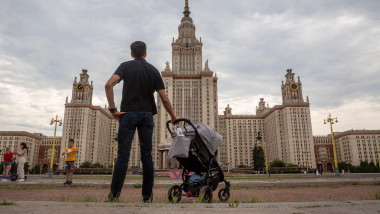Imagine cu un bărbat care plimbă un cărucior de bebeluș și se uită la clădirea Universității de Stat din Moscova situată în centrul Moscovei. Foto: Profimedia Images