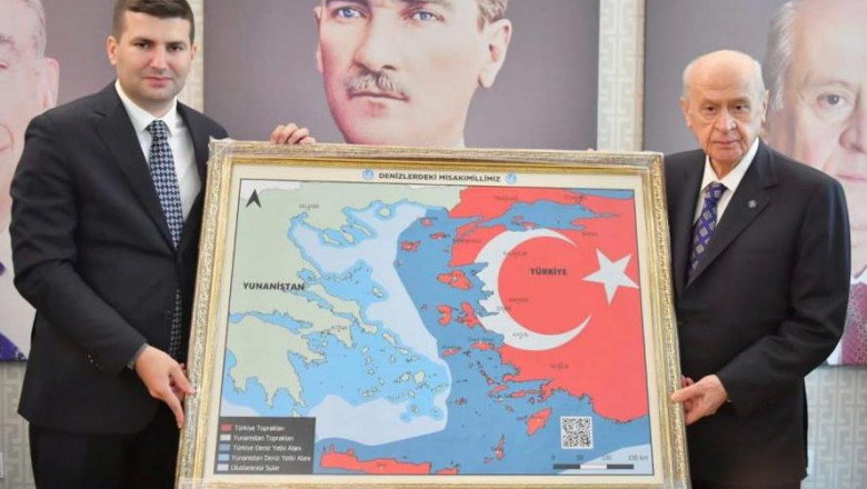 Devlet Bahceli (dreapta) alături de o hartă în care insule grecești sunt reprezentate cu rosu, ca apaținând Turciei