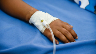 mână cu branulă pe un pat de spital