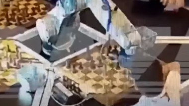 Un copil joacă șah cu un robot.