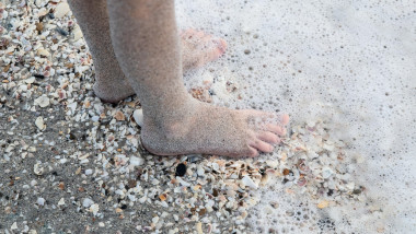 Copil cu picioarele în apă pe plajă