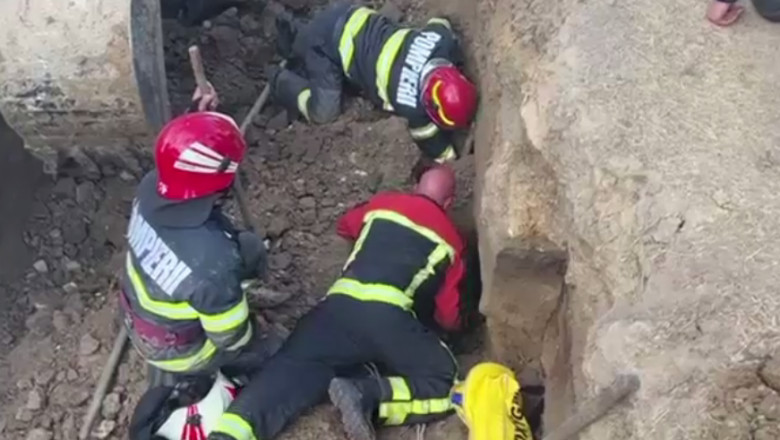 Angajați ISU incearcă să scoată un om de sub un mal de pământ surpat.