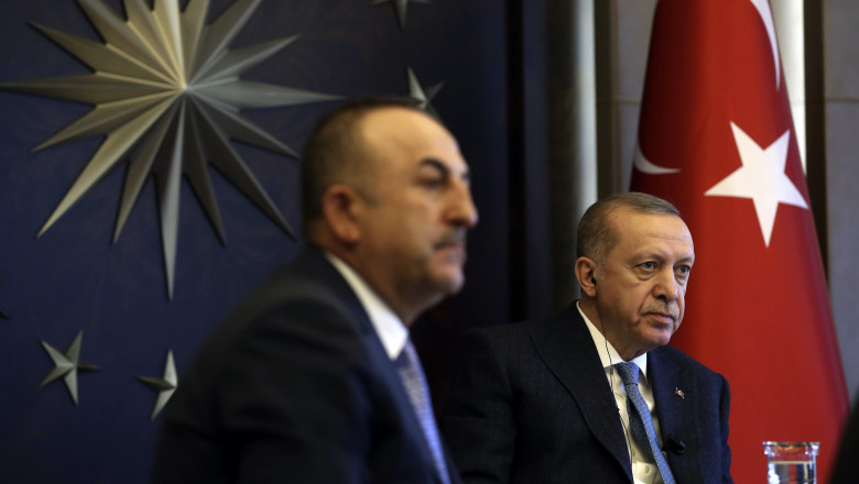 Turkish President Recep Tayyip Erdogan, right, flanked by Foreign Minister Mevlut Cavusoglu, cu steagul turciei pe fundal