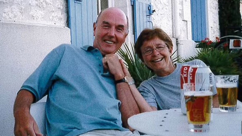 Graham Mansfield și soția lui, Dyanne, zambesc la camera in gradina, cu bere pe masa