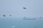 elicoptere militare și un portavion în depărtare